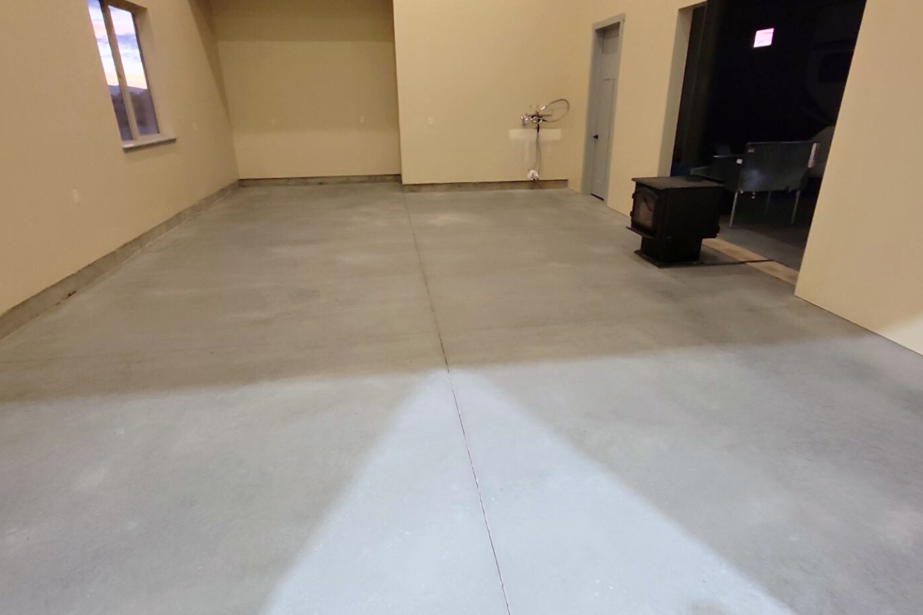 A room with a concrete floor and a wood stove in it.