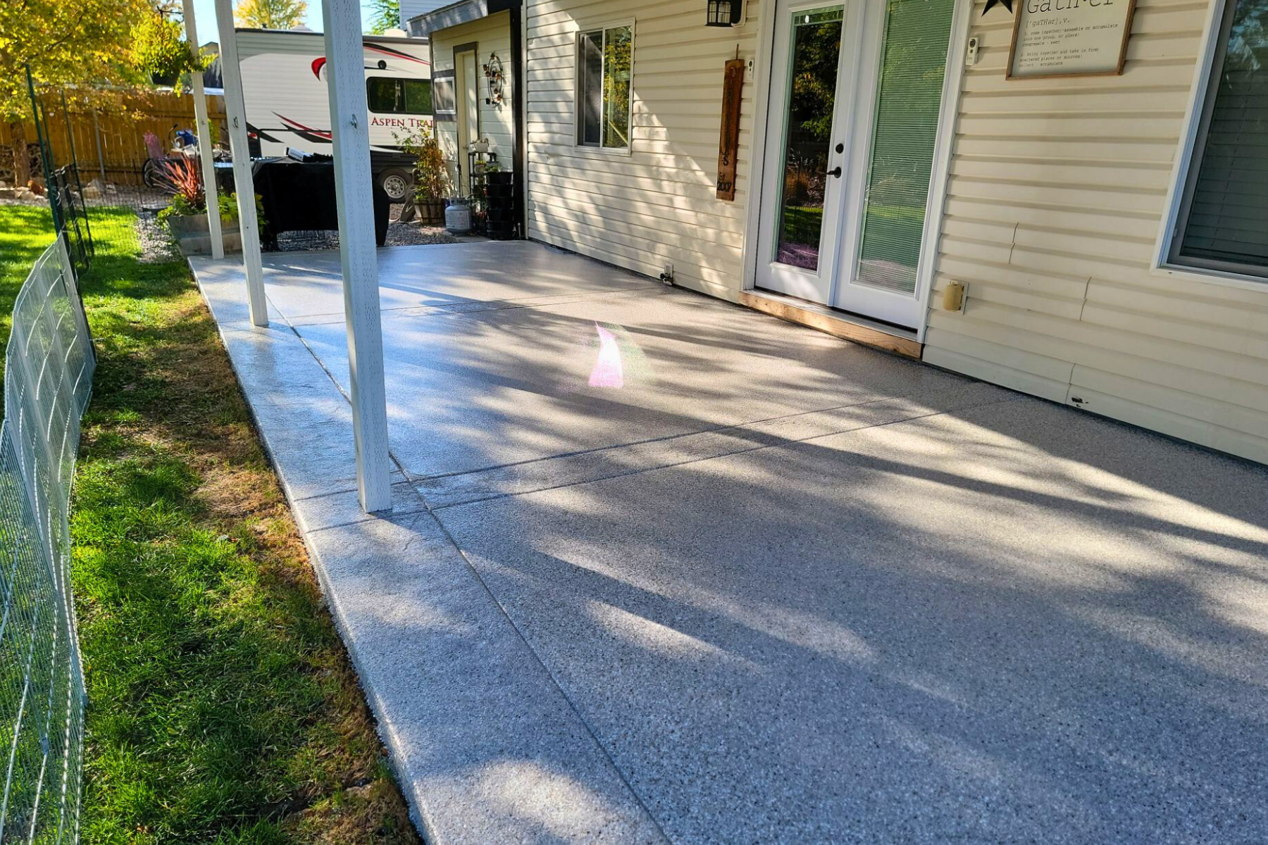 A concrete patio in front of a house with a fence.