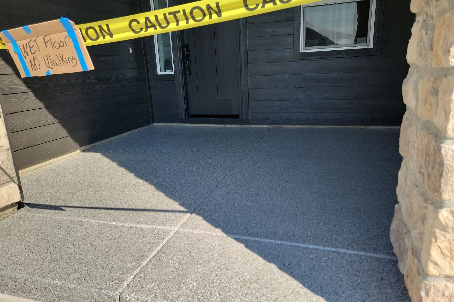 A yellow caution tape is hanging on the sidewalk in front of a house.