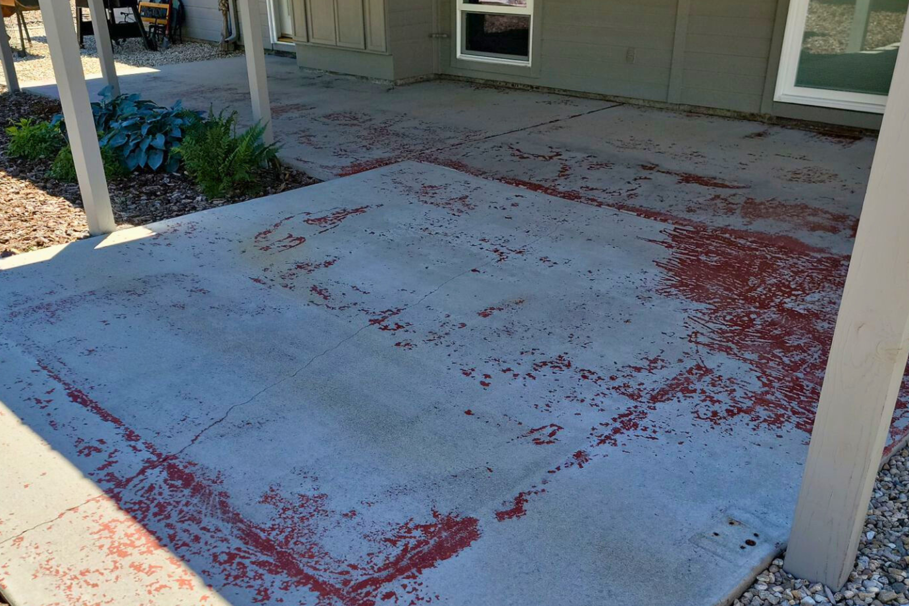 A concrete patio with red paint on it in front of a house.