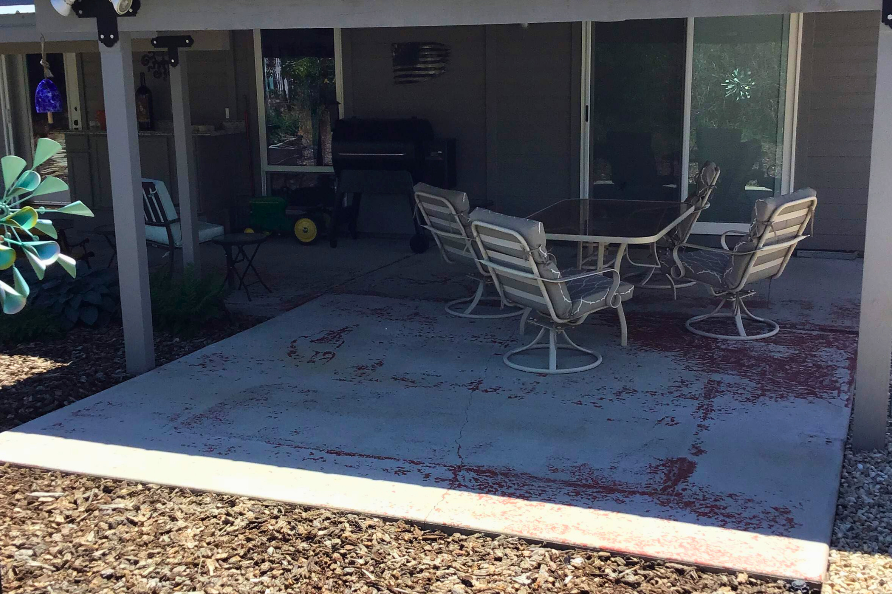 A patio with a table and chairs under a covered patio cover.