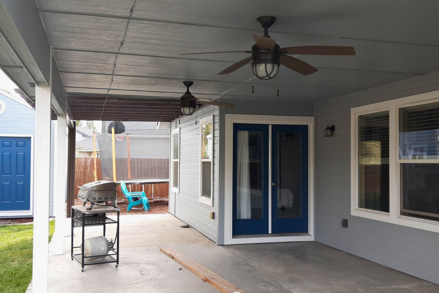 There is a ceiling fan on the patio of a house.