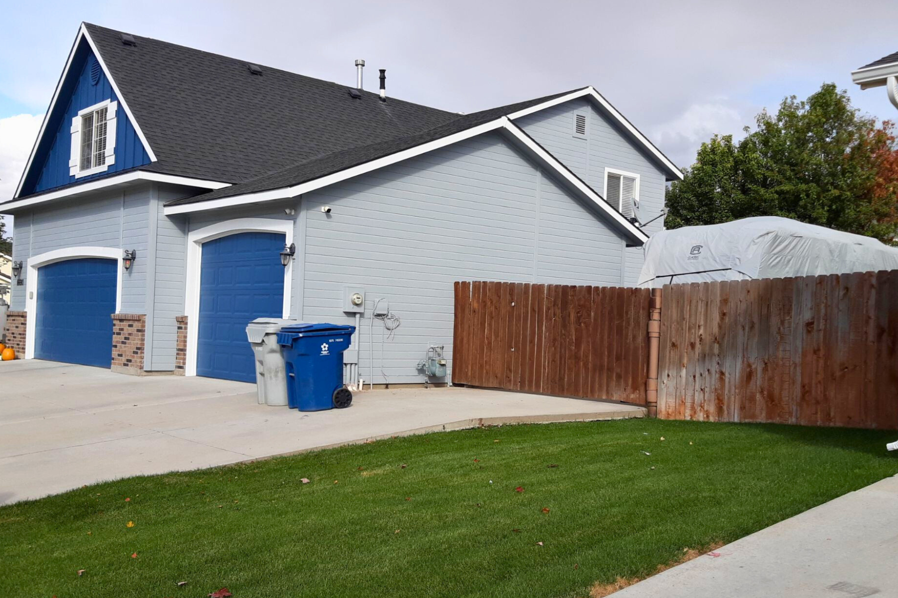 A house with blue garage doors and a wooden fence