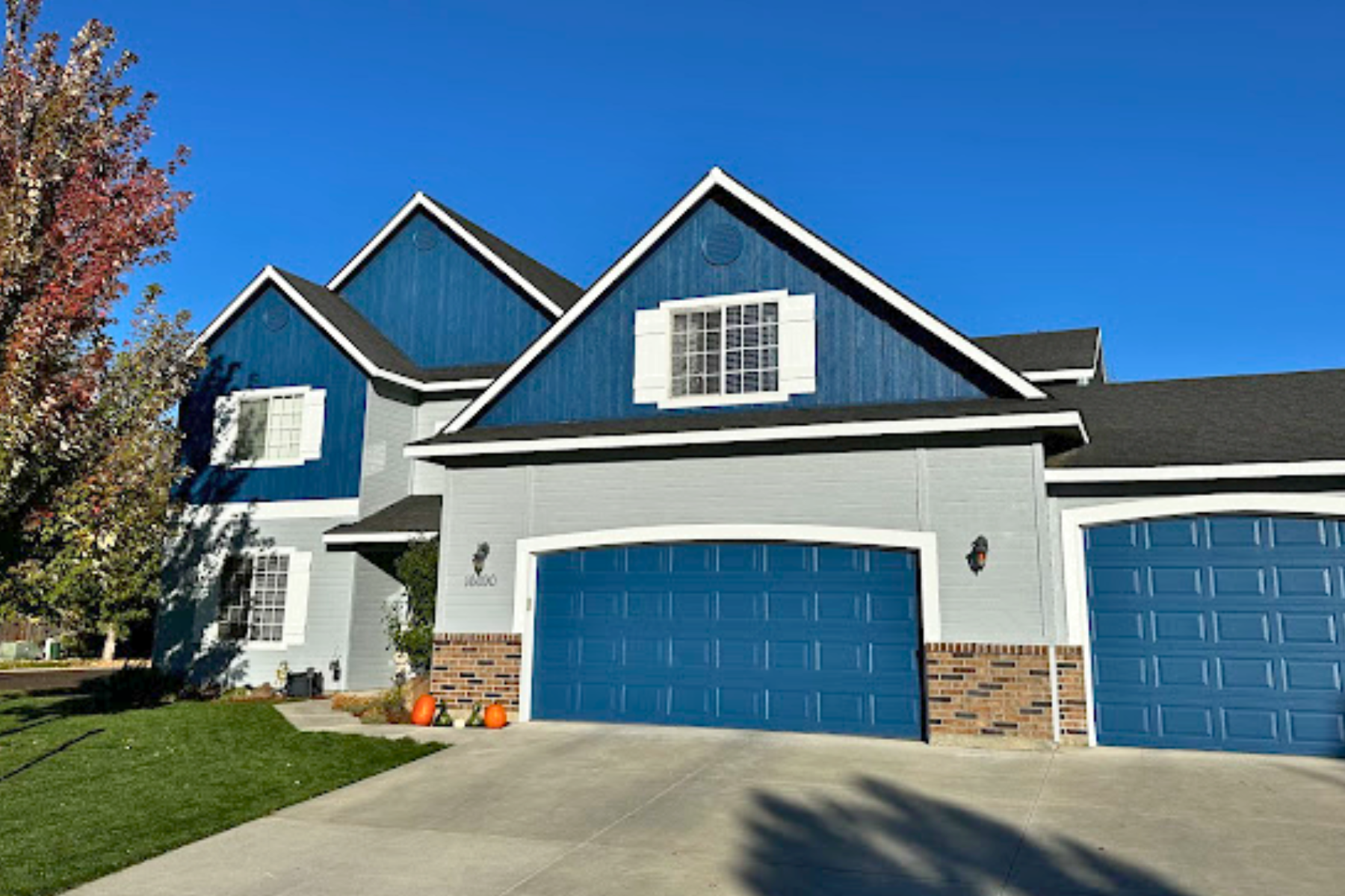 A large house with blue siding and blue garage doors.