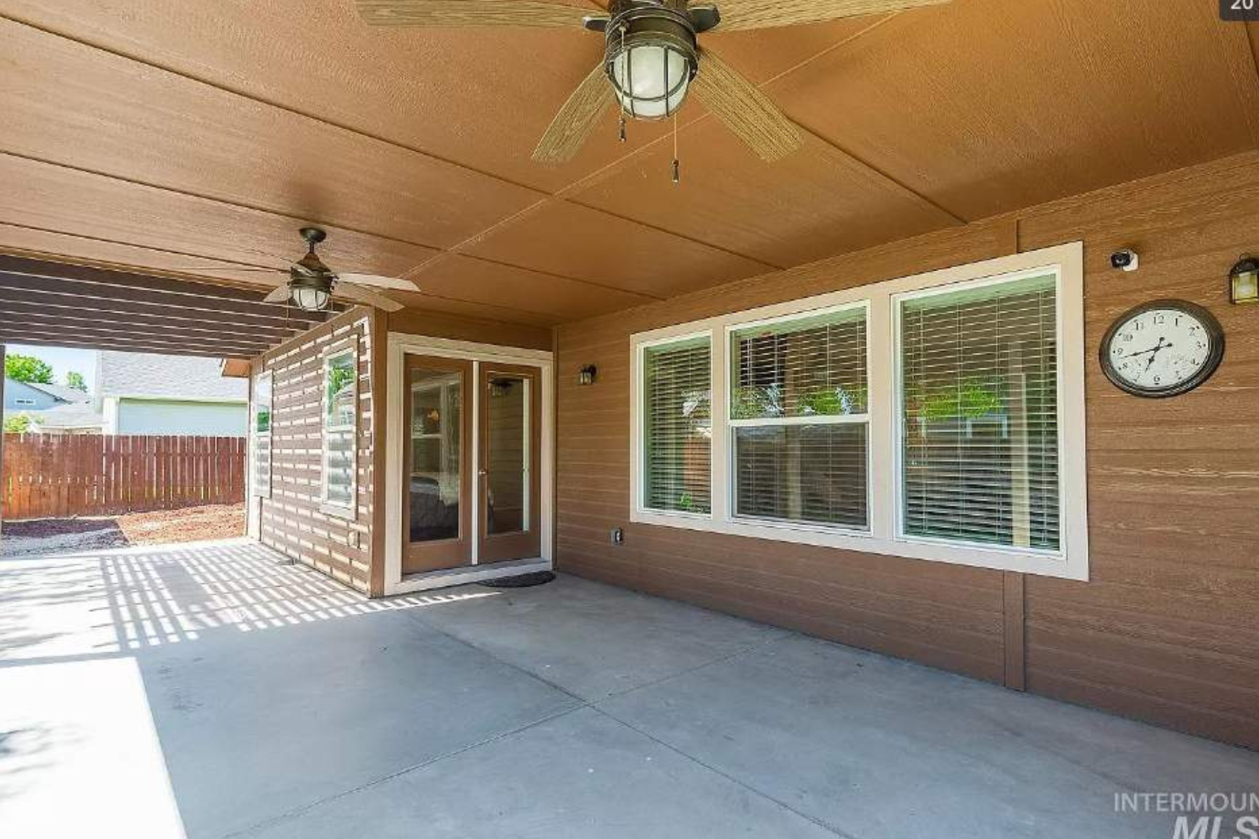A patio with a ceiling fan and a clock on the wall.