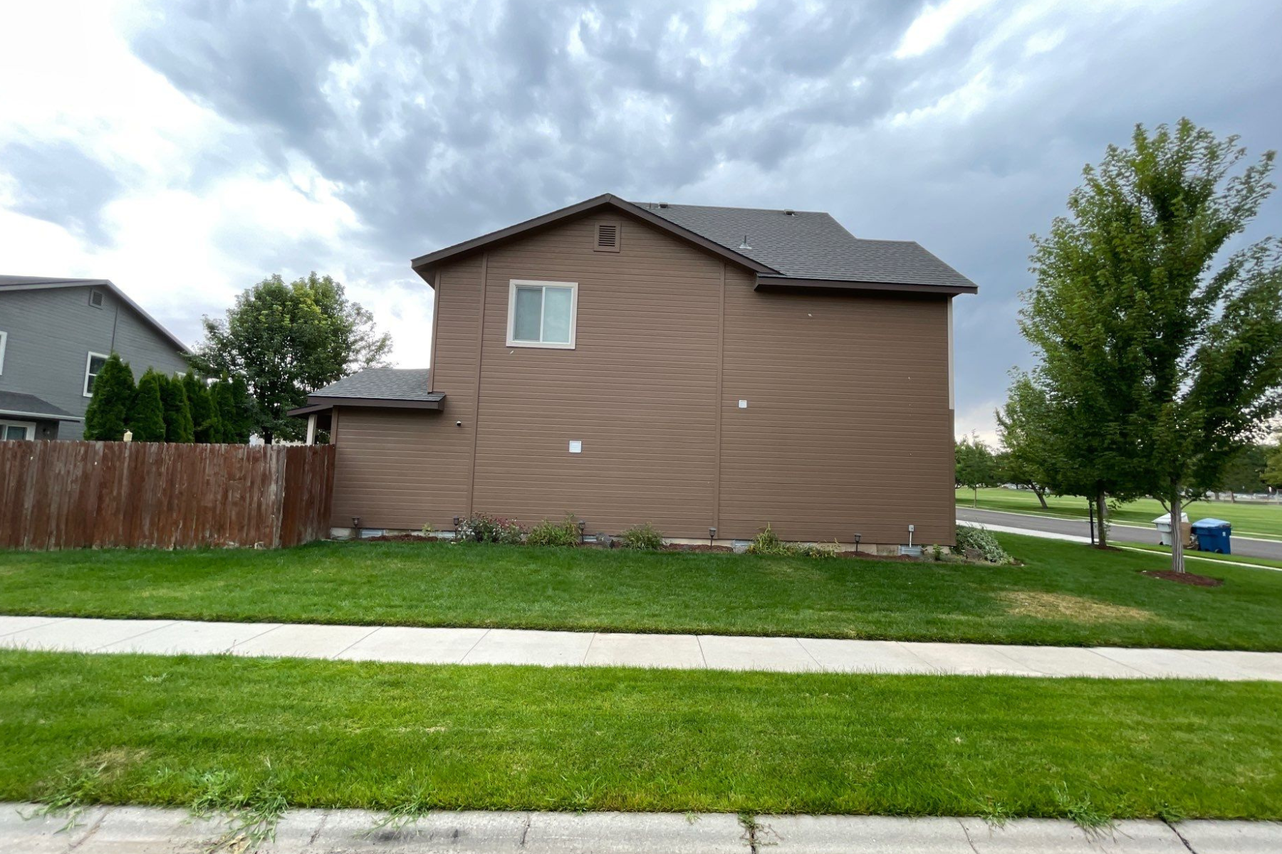 A house with a fence in front of it and a cloudy sky in the background.