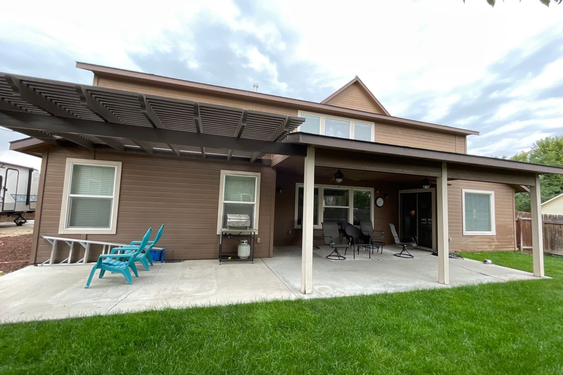The back of a house with a covered patio and chairs.