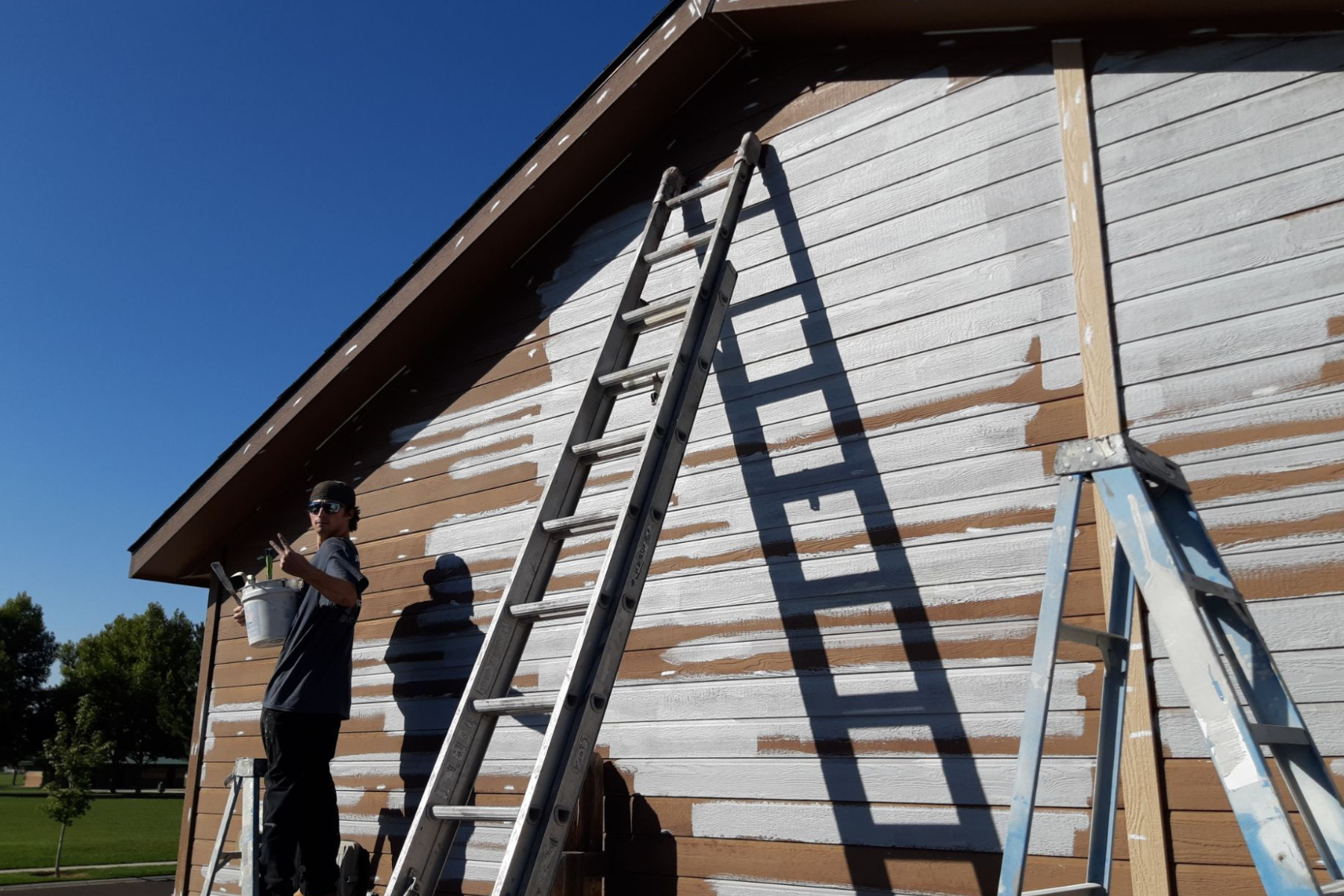 A man on a ladder paints the side of a building