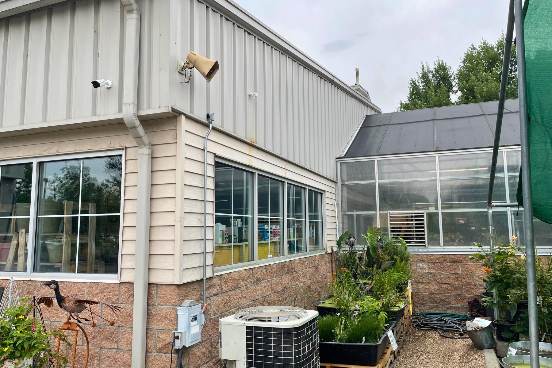 A building with a lot of windows and a greenhouse in the background.
