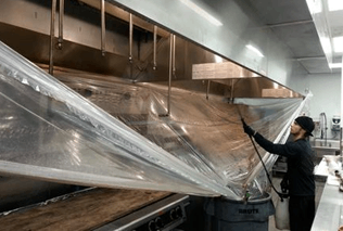 A man is cleaning a kitchen hood with a plastic bag. A man is cleaning a kitchen hood with a plastic bag.