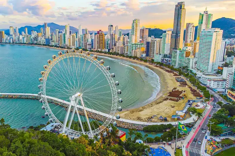 Uma vista aérea de uma praia com uma cidade ao fundo.