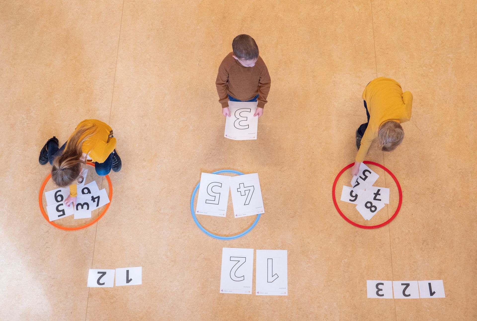 Een groepje kinderen speelt een spelletje op de grond.