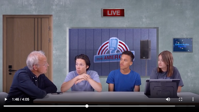 Een groep mensen zit aan een tafel voor een bord met de tekst live