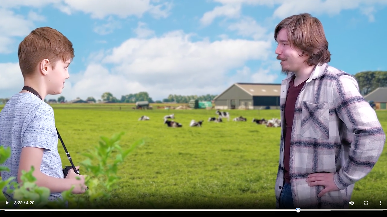 Een man en een jongen staan ​​in een veld met koeien op de achtergrond.