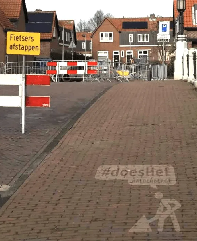 Een straatbeeld met bouwafzettingen, een bord met 