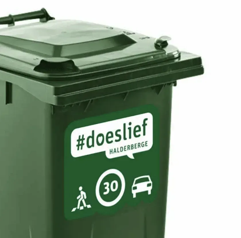 Een groene vuilnisbak met een sticker waarop staat 