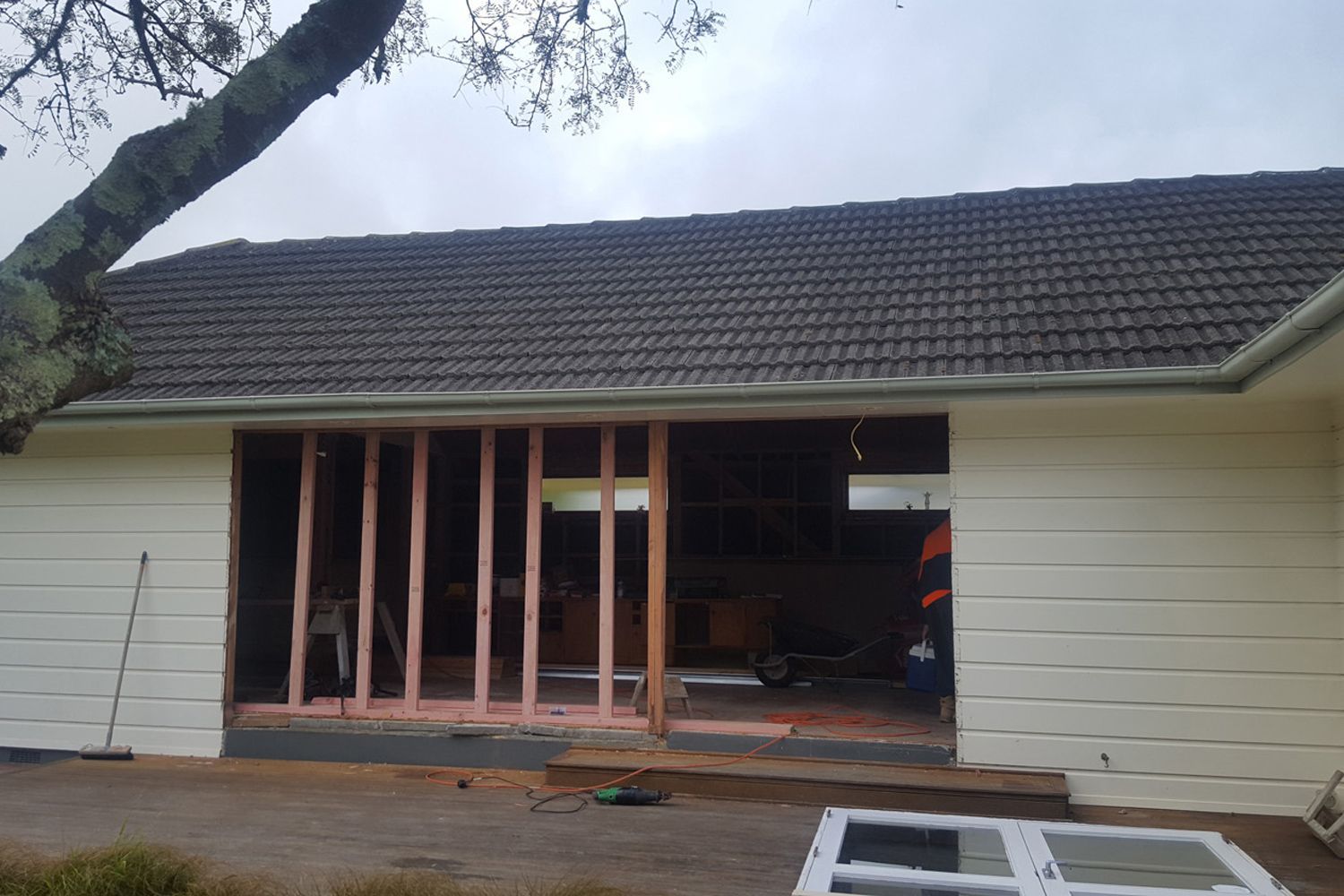 Exterior wall being remodeled with a large opening; exposed framing and a roof.