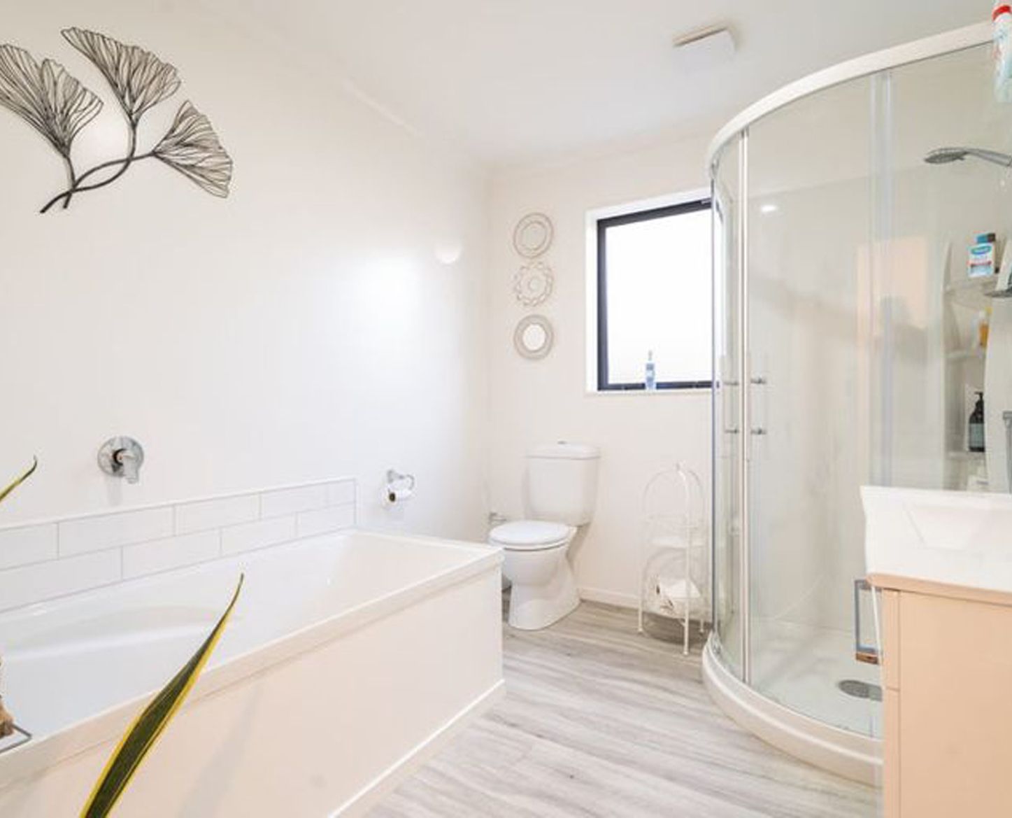 Bright white bathroom with a tub, toilet, and glass shower.
