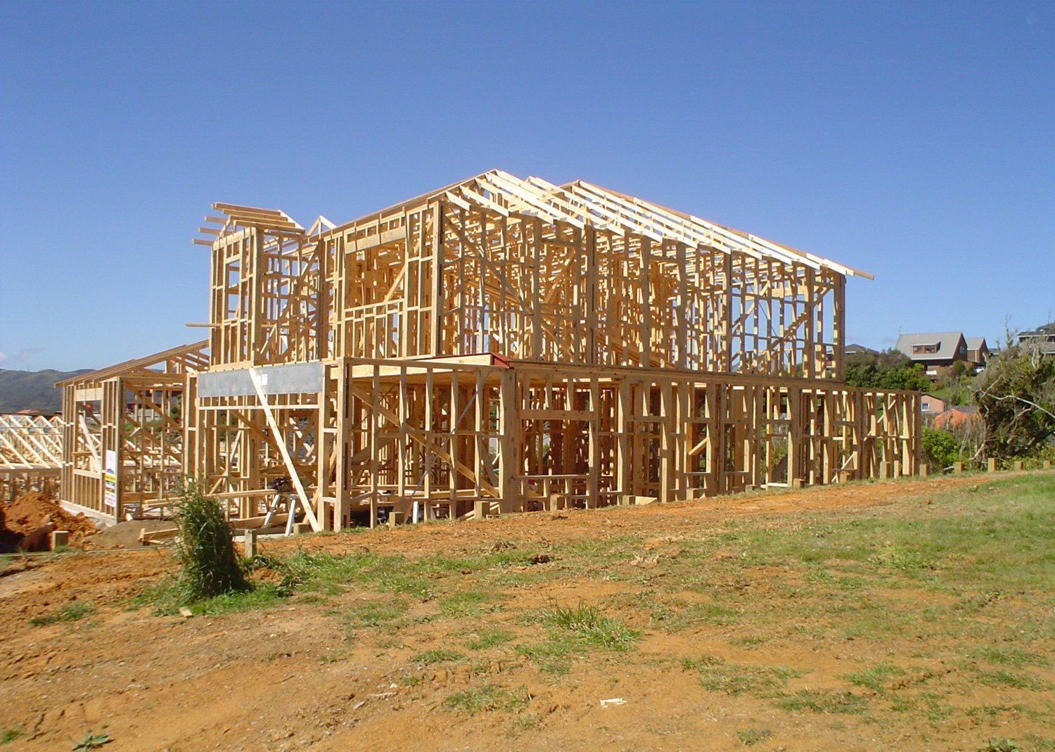 Wooden house frame under construction against a clear blue sky.