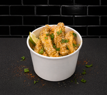 White cup of seasoned fried snacks with green garnish on a black surface