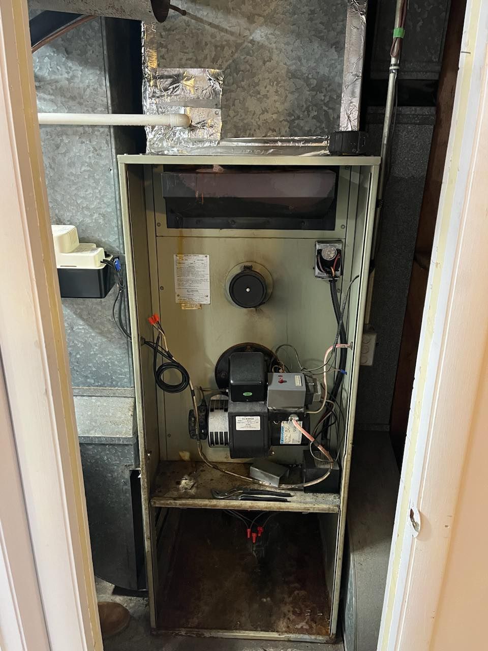 A dirty air conditioner is sitting inside of a closet.
