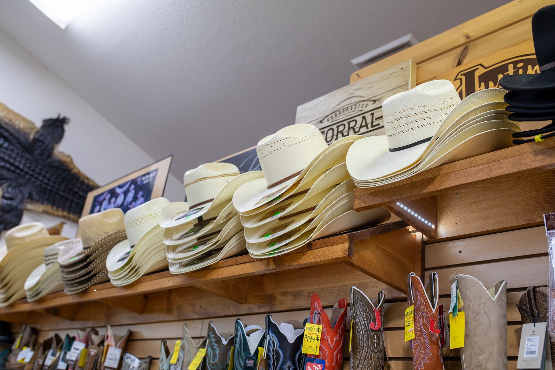 Shelves stacked with straw hats in a shop, with hanging items below.