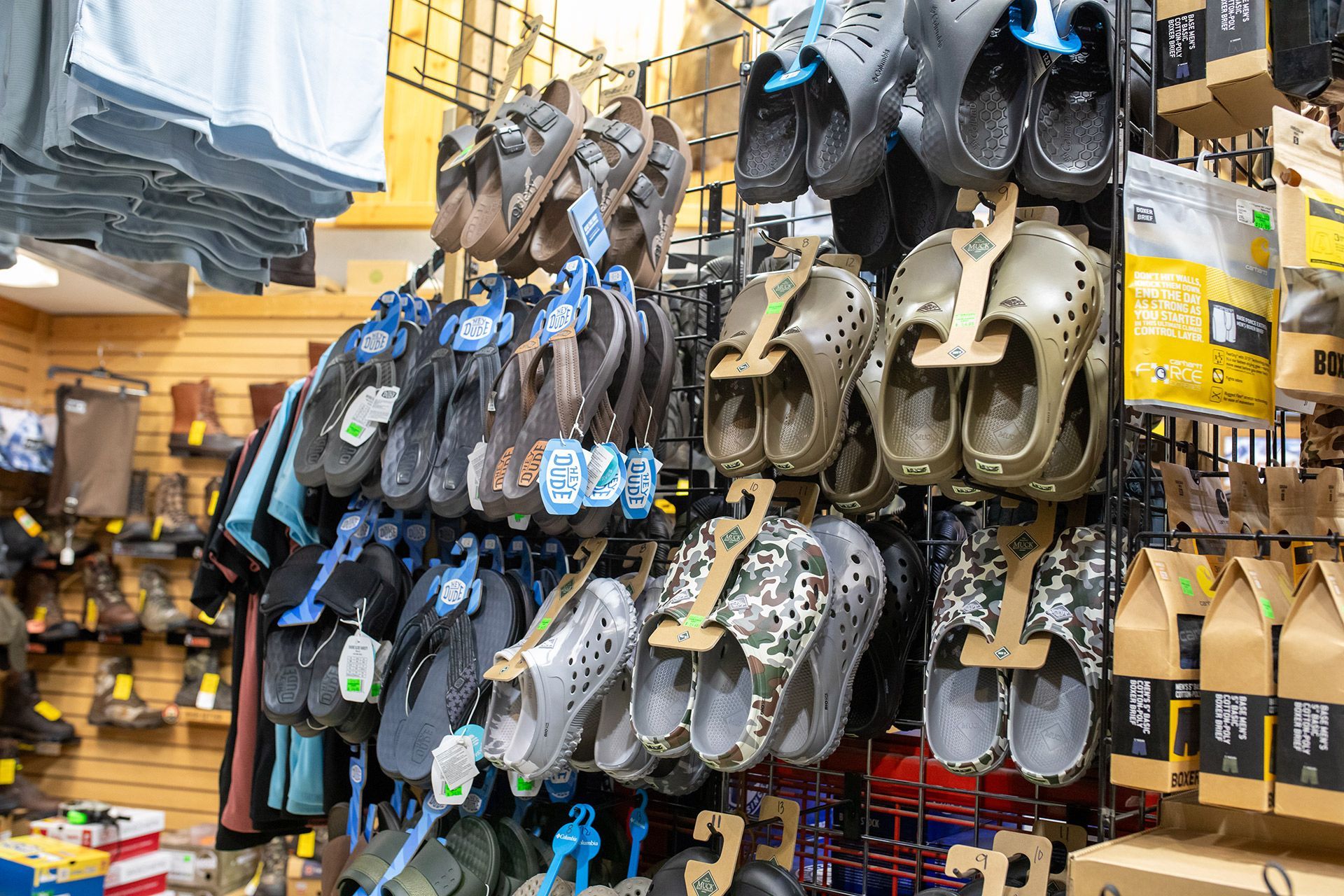Rack of assorted sandals and clogs hanging in a store aisle