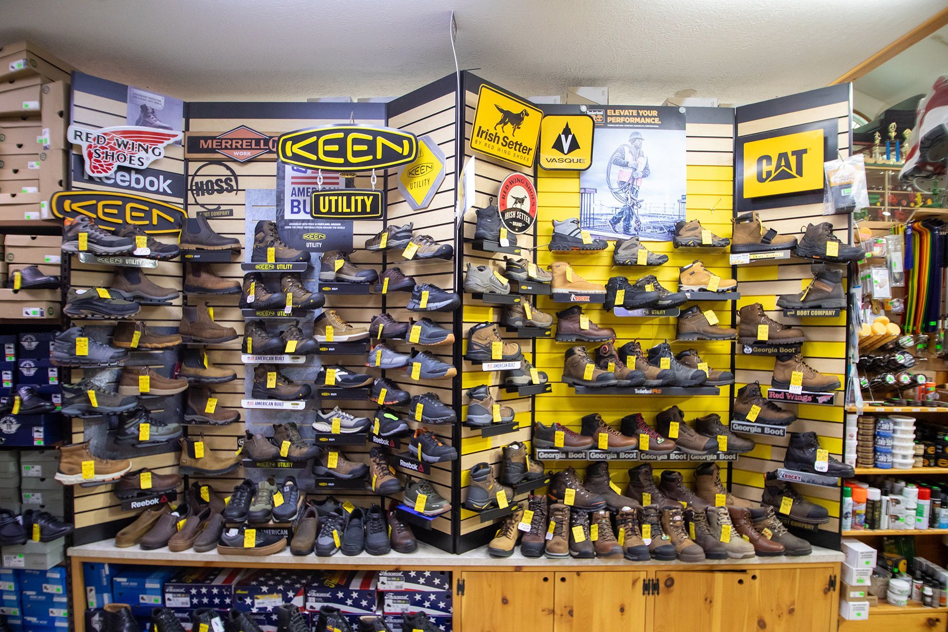 Wall of yellow-and-black KEEN and CAT work boots displayed on shelves in a shoe store