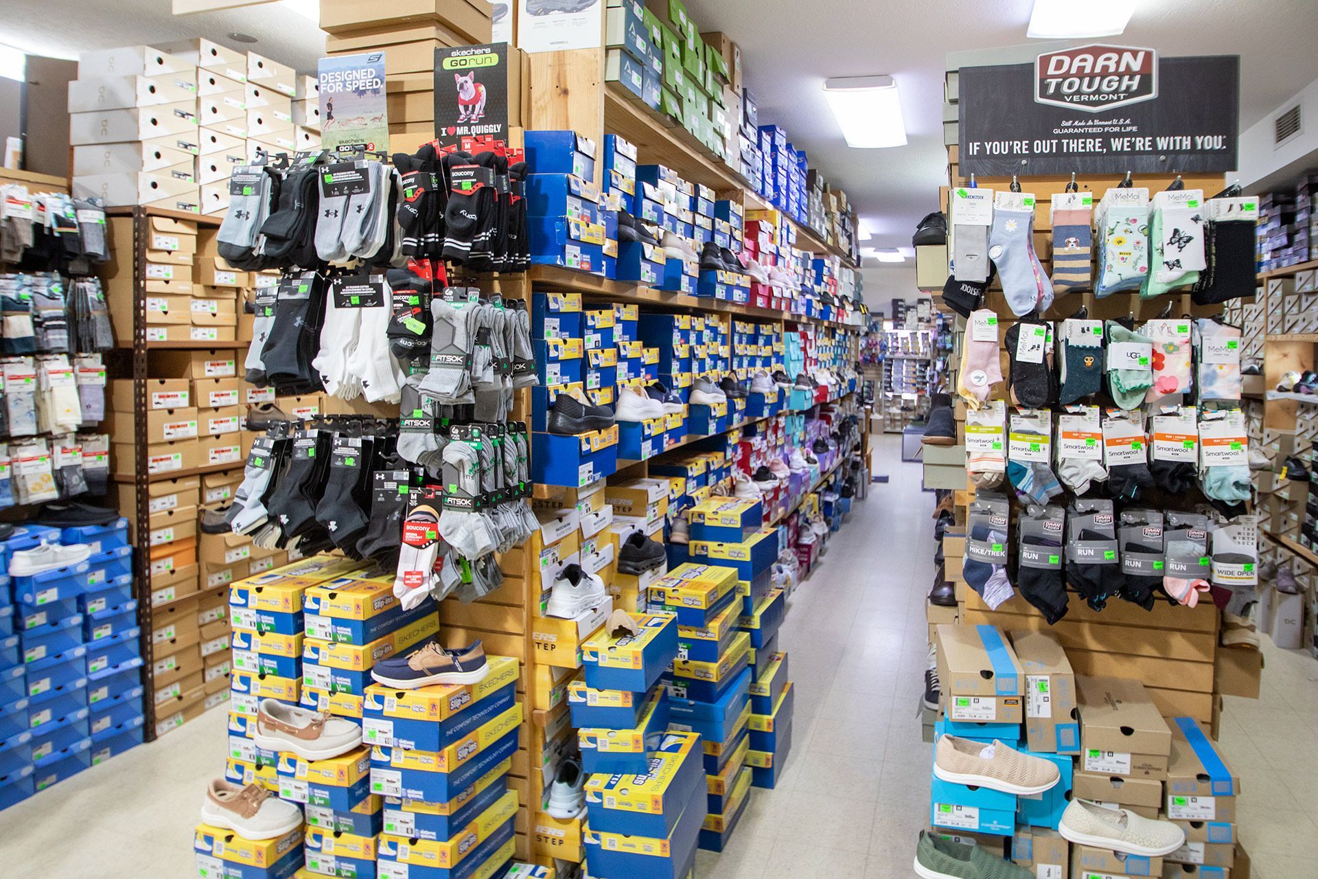 Narrow store aisle packed with stacked boxes and hanging packaged goods on both sides