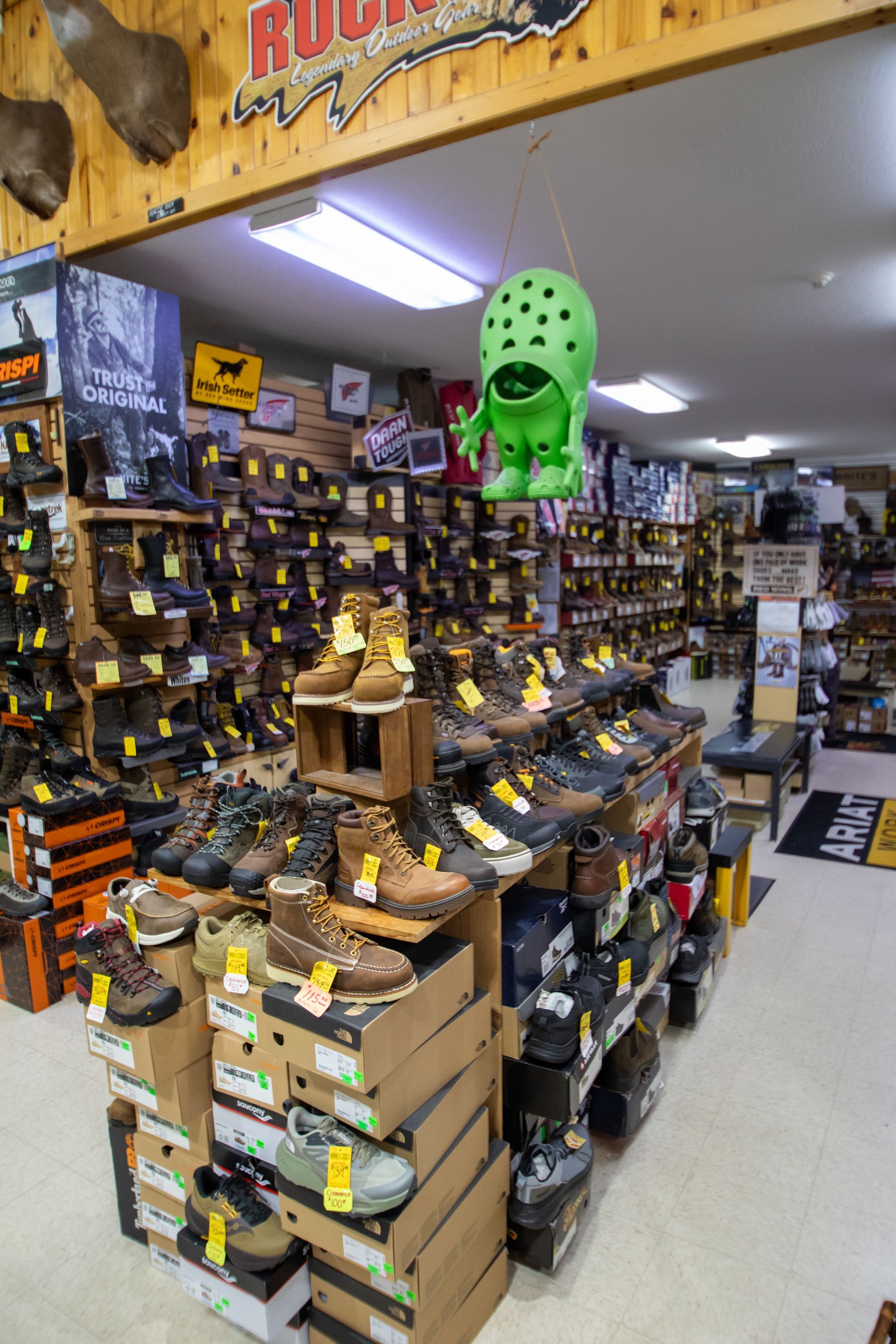 Hardware store aisle with stacked boxes, tool displays, and a bright green mask hanging overhead