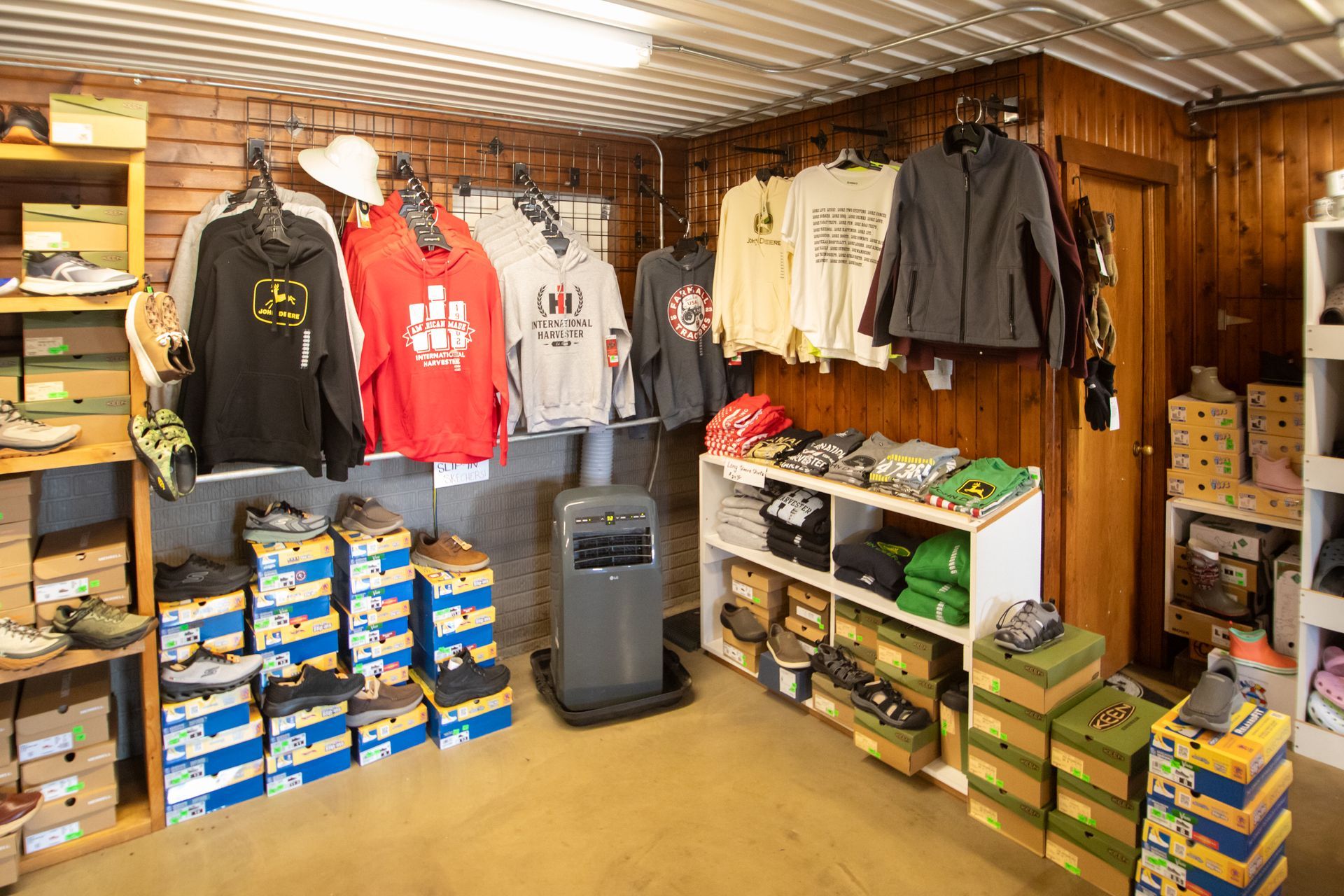 Clothing and gear display in a wood-paneled shop, with hoodies, jackets, boxes, and shelves of merchandise.