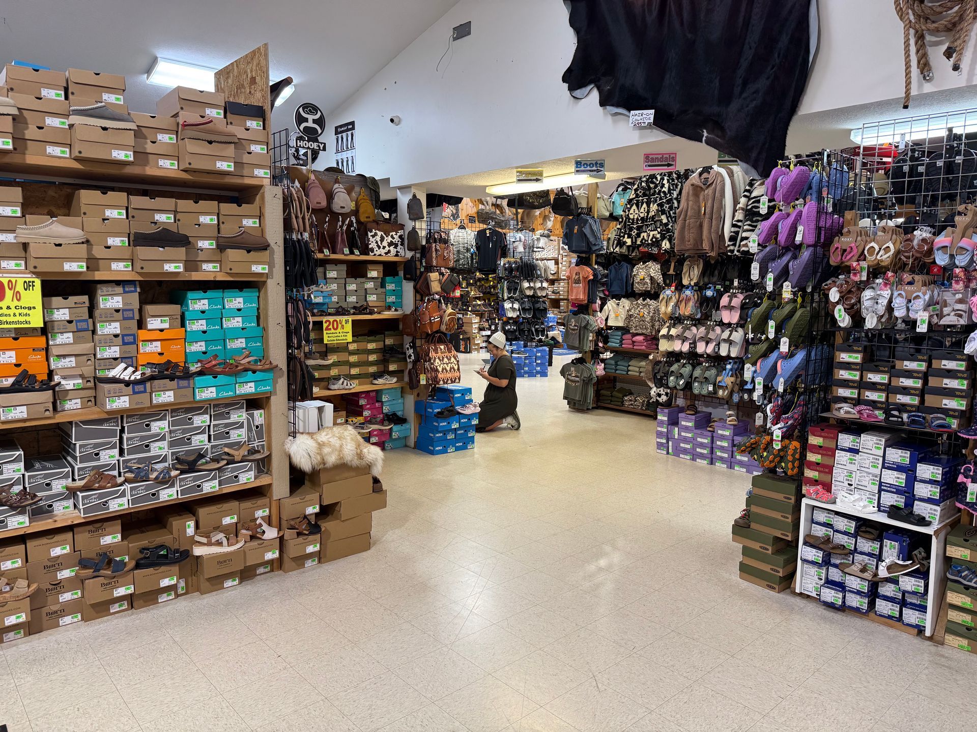 A cluttered retail store aisle with shelves of boxes, clothing, and accessories.