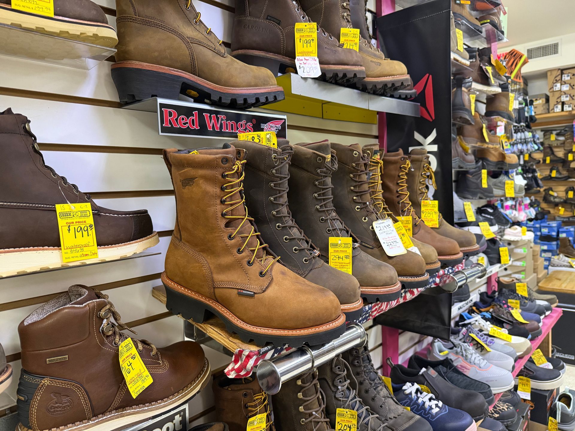 Boots and work shoes displayed on store shelves, including tan and brown lace-up boots with sale tags.