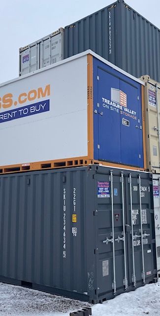 Open yellow shipping container filled with stacked cardboard boxes, with empty wooden pallets in front.