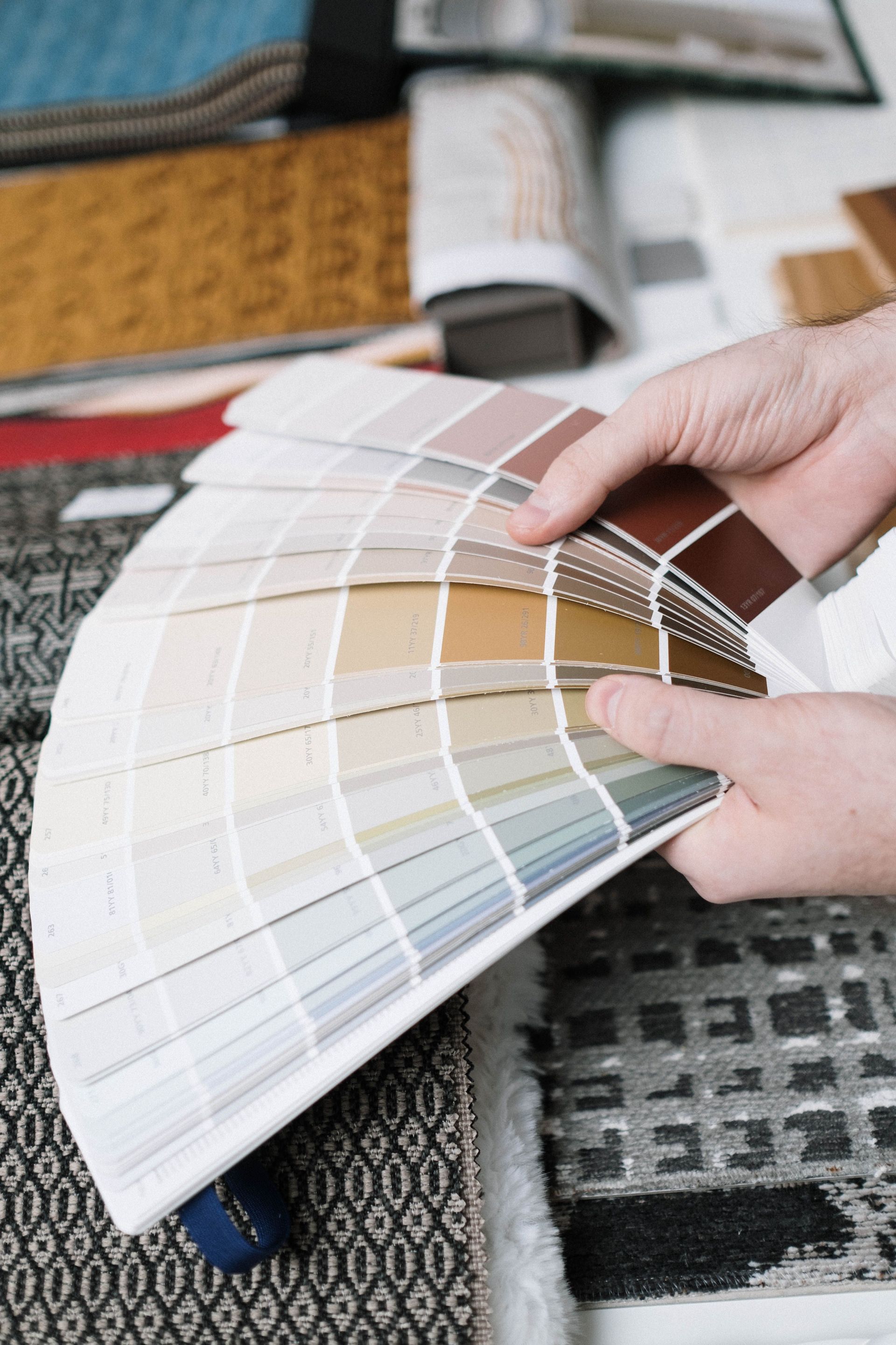 Hands fanning out color swatches on a table next to fabric samples