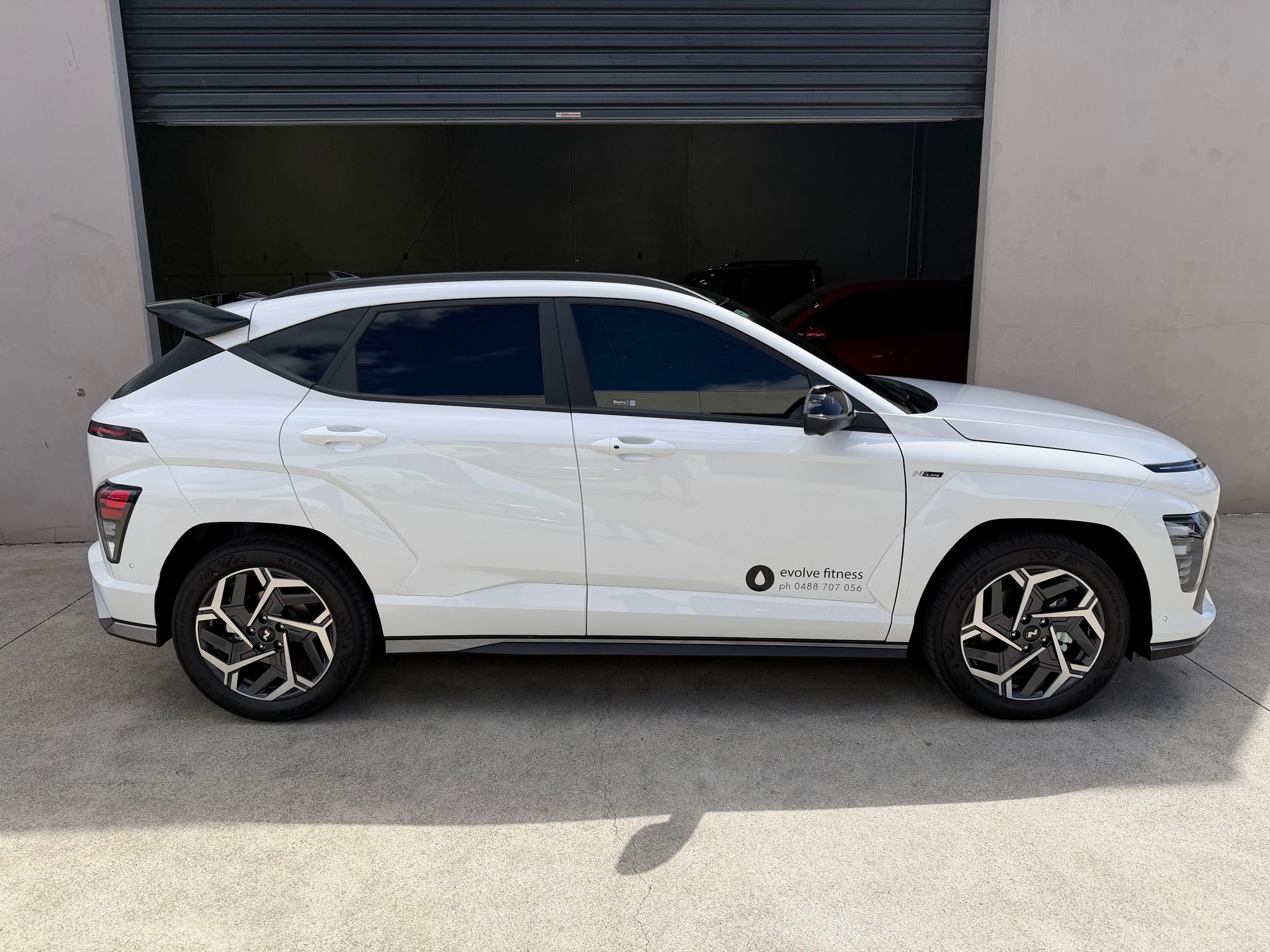 White SUV parked side view outside a garage with a dark door — Magic Tintz in Moonah, TAS