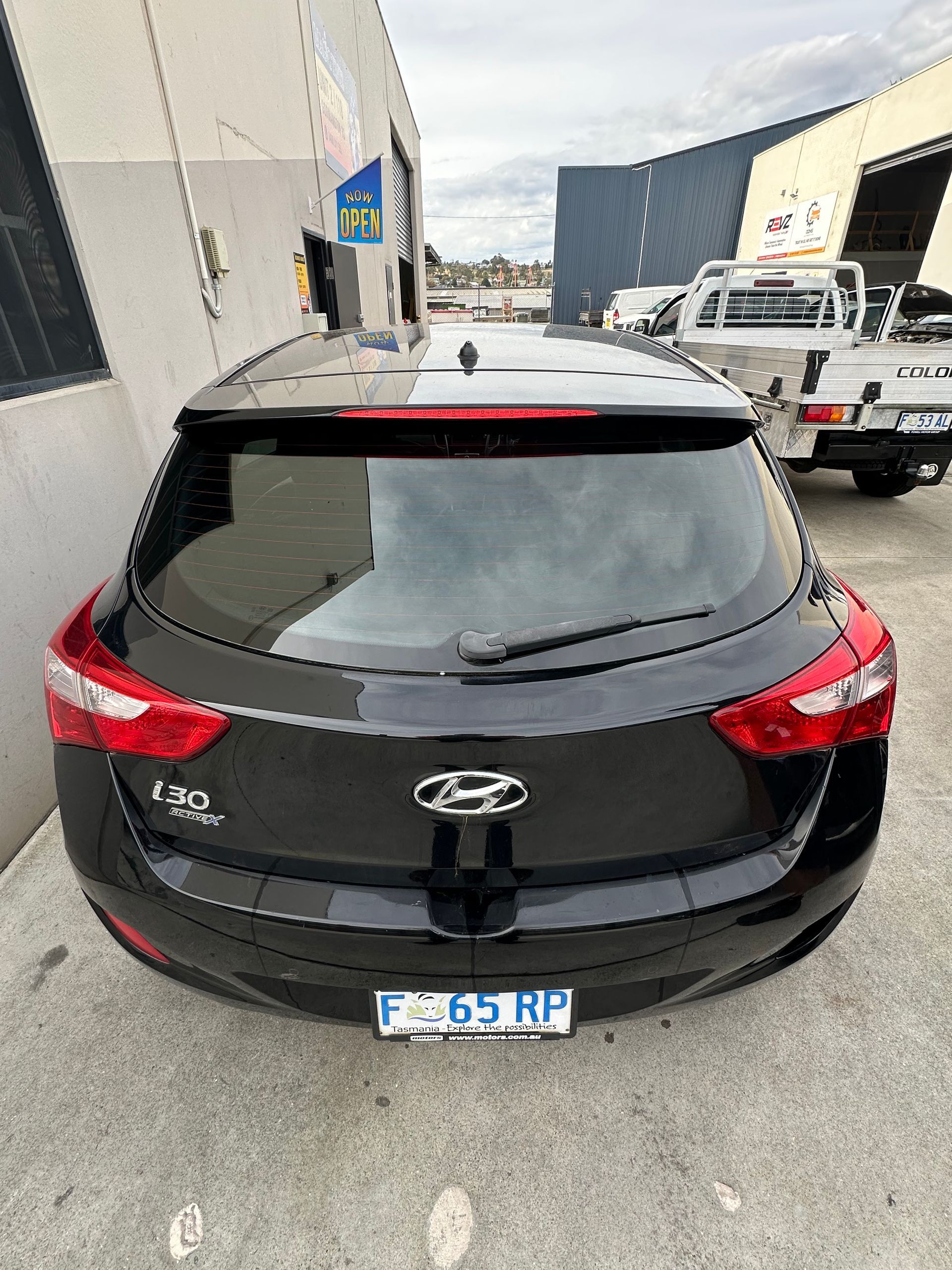 Black Hyundai hatchback parked in an industrial lot, rear view. — Magic Tintz in Moonah, TAS