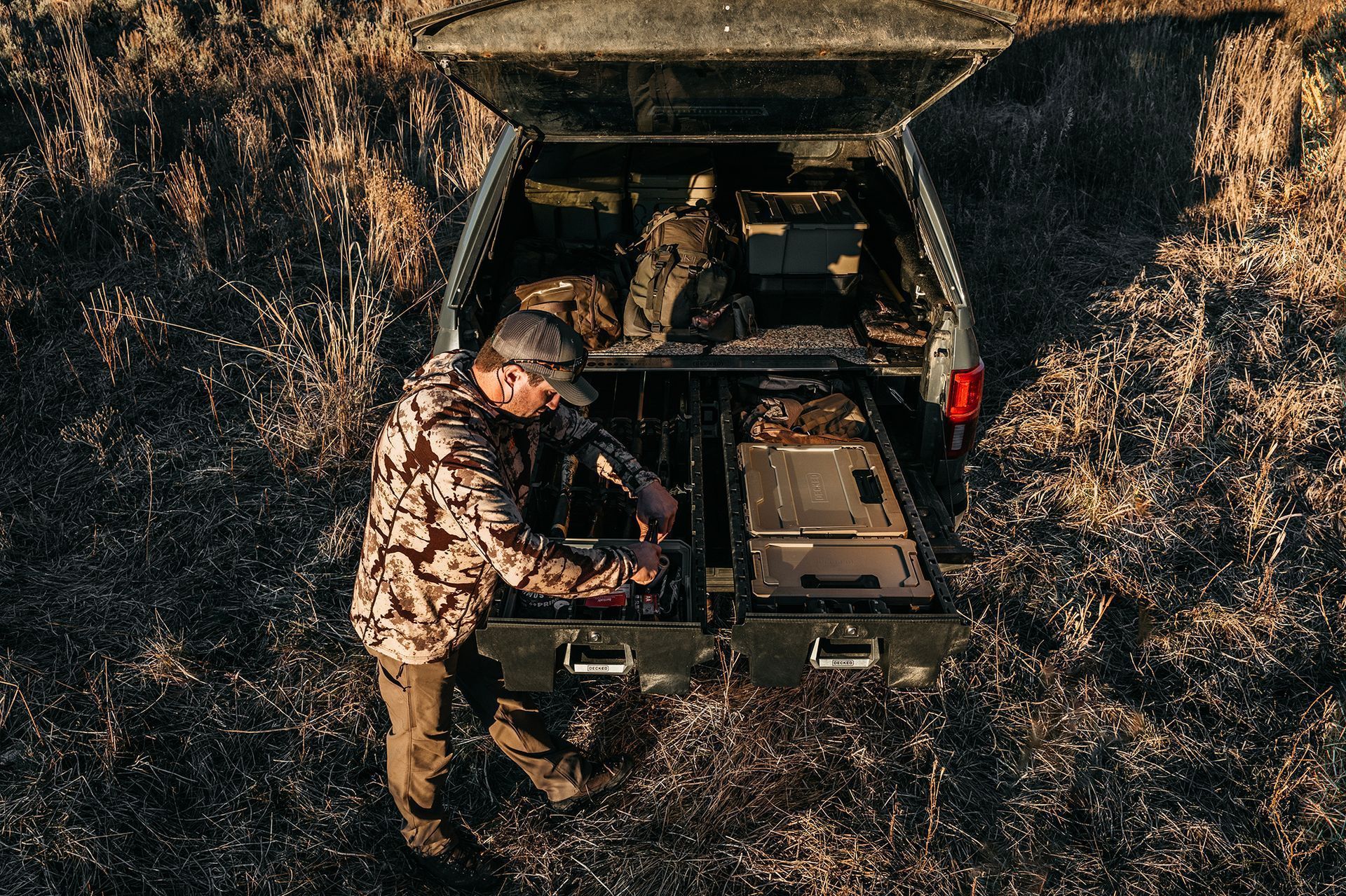 A man is standing next to a truck with the trunk open.