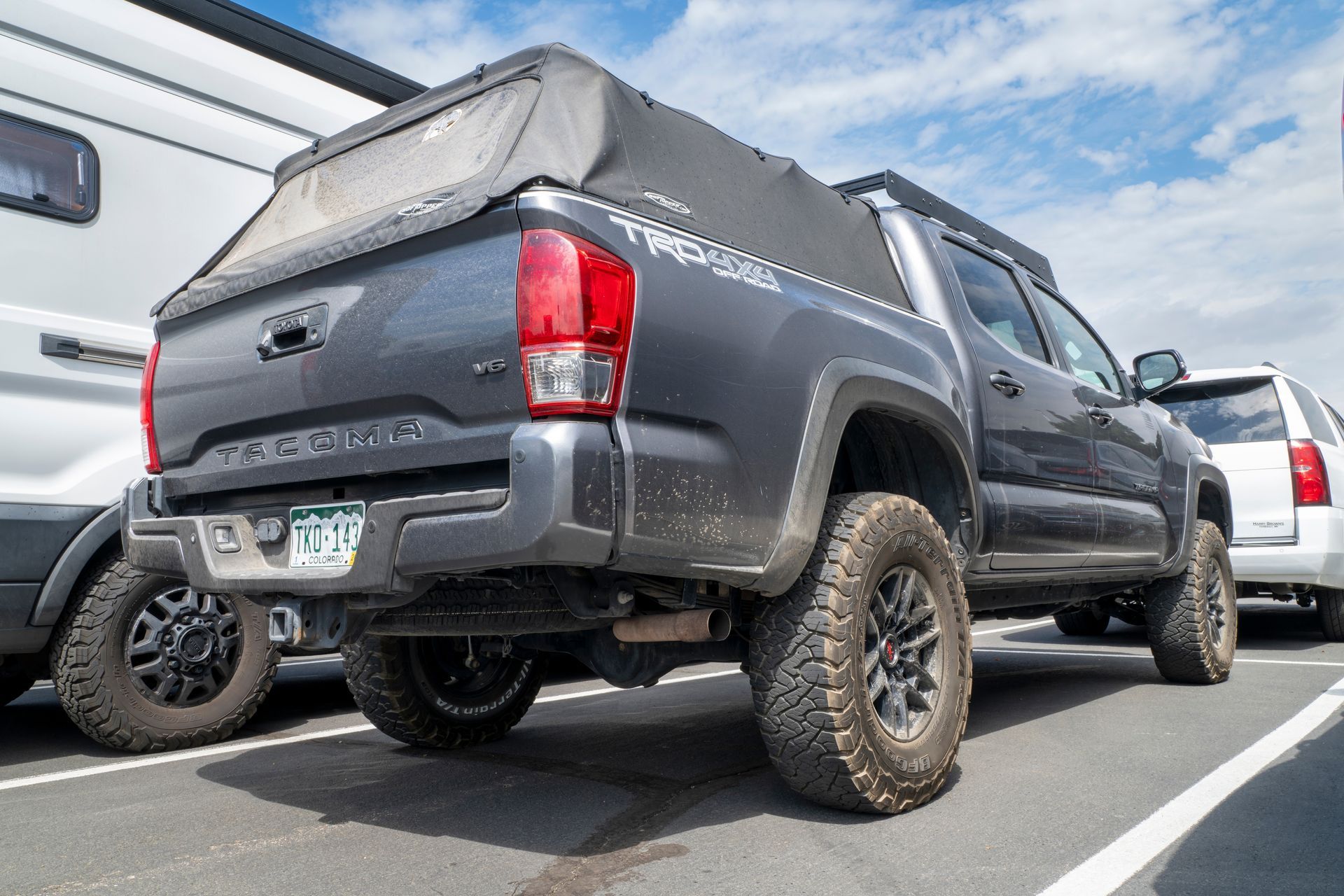 Gray Toyota Tacoma pickup truck parked in a lot, rear view with lifted suspension and off-road tires