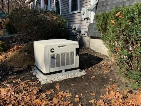 MJS Electrical Services - A generator is sitting in the dirt in front of a house.