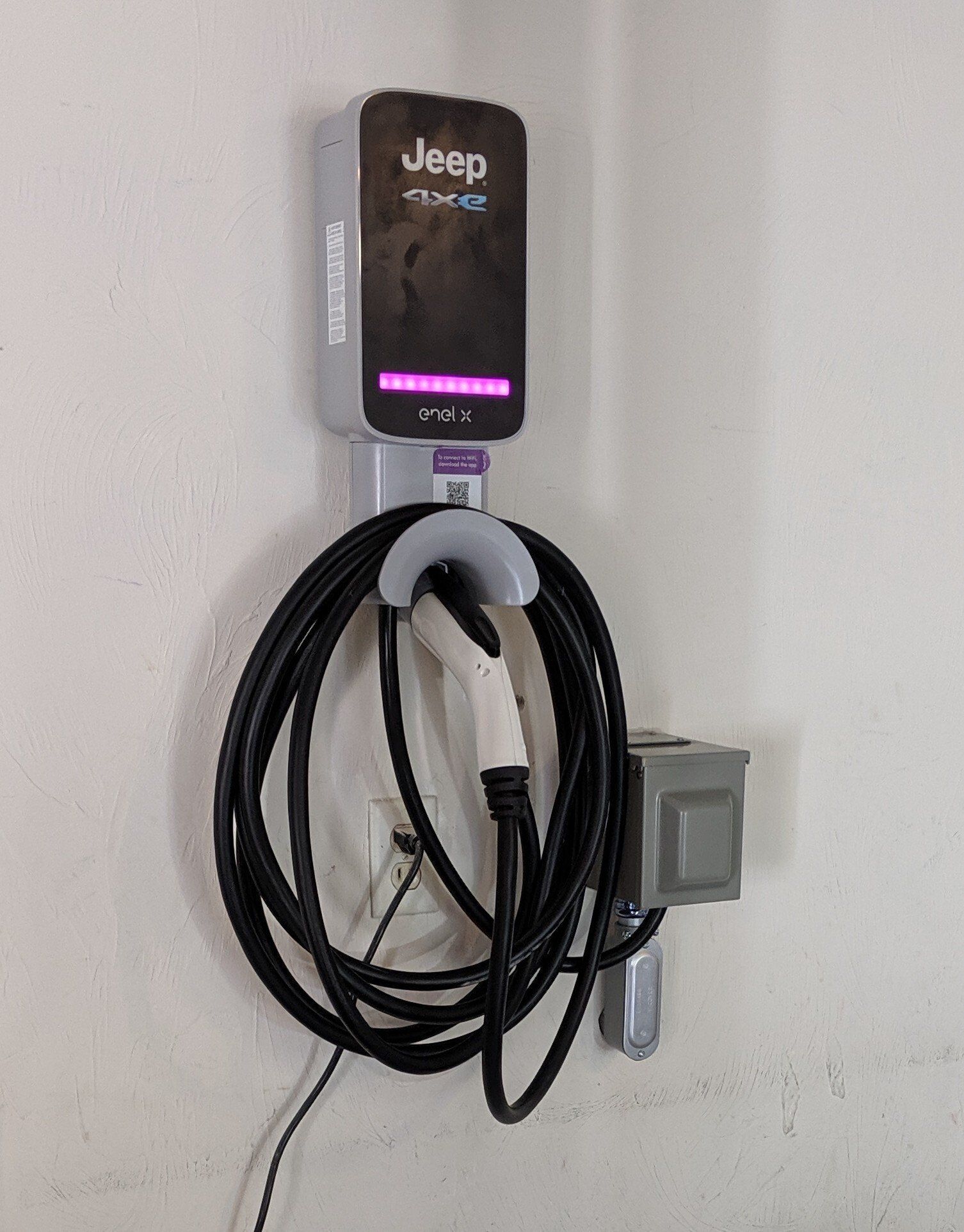 MJS Electrical Services - A jeep electric car charger is hanging on a wall.