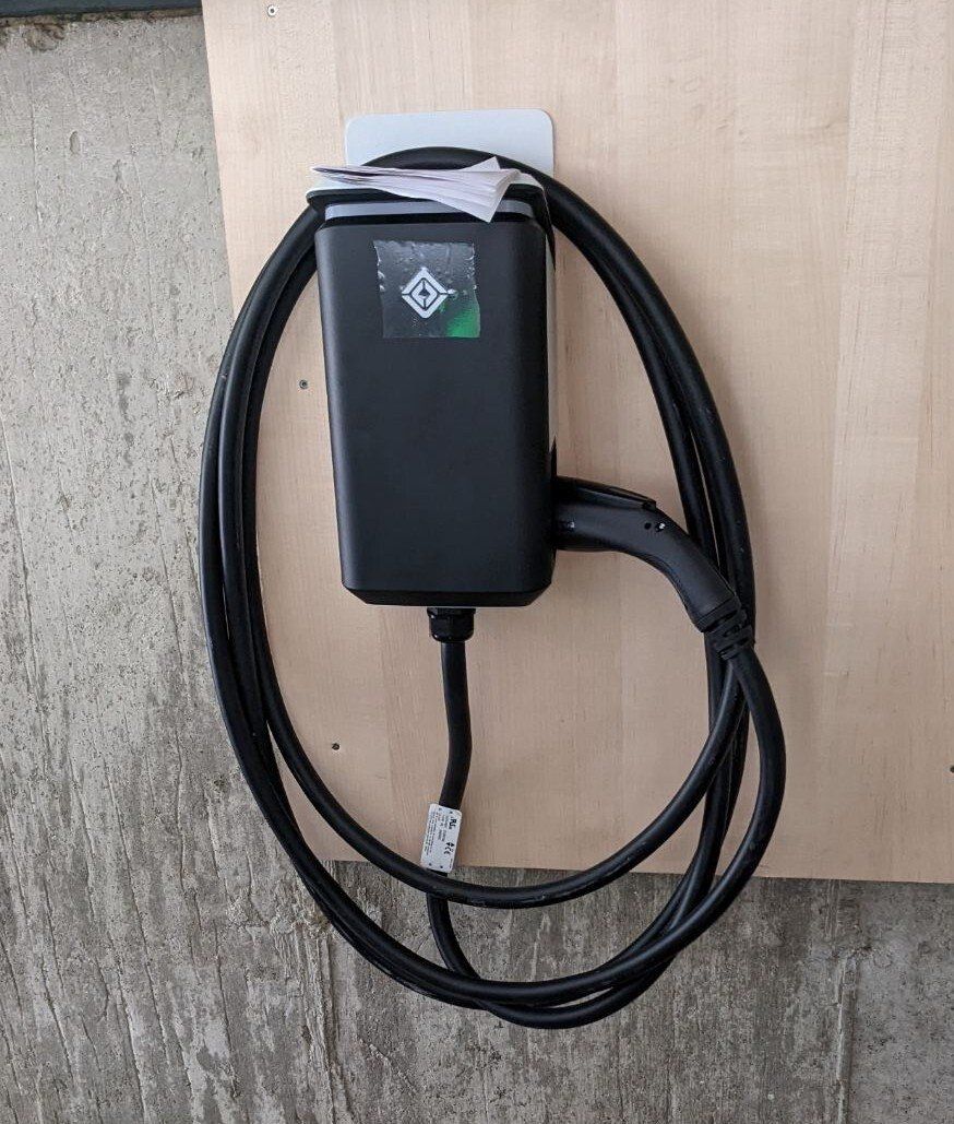 MJS Electrical Services - A black charger is attached to a wooden wall