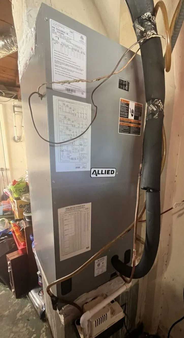 Indoor HVAC unit with labels, wiring, and black insulated ductwork in a utility closet