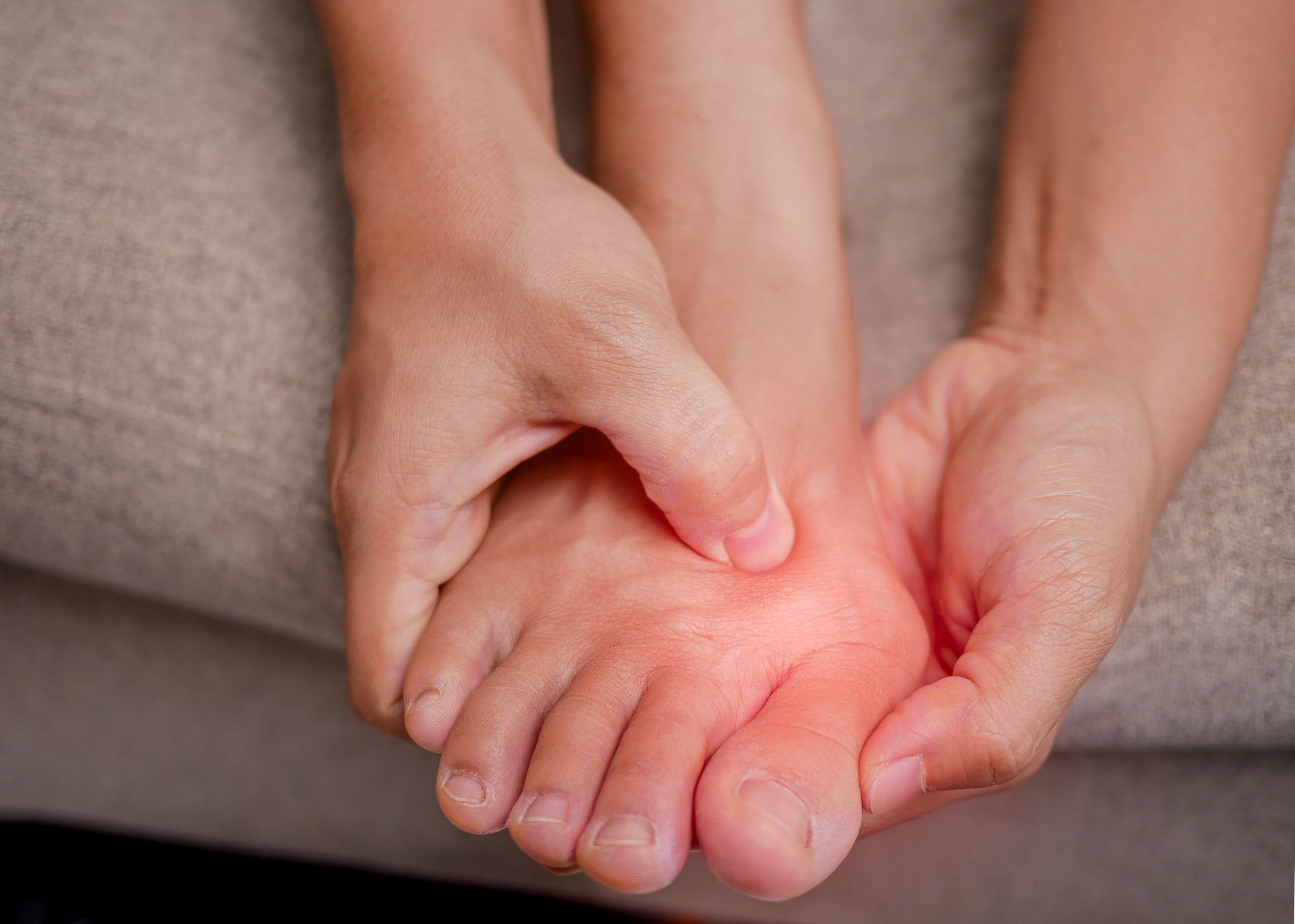 Person holding their foot, likely experiencing pain. Redness indicates inflammation.