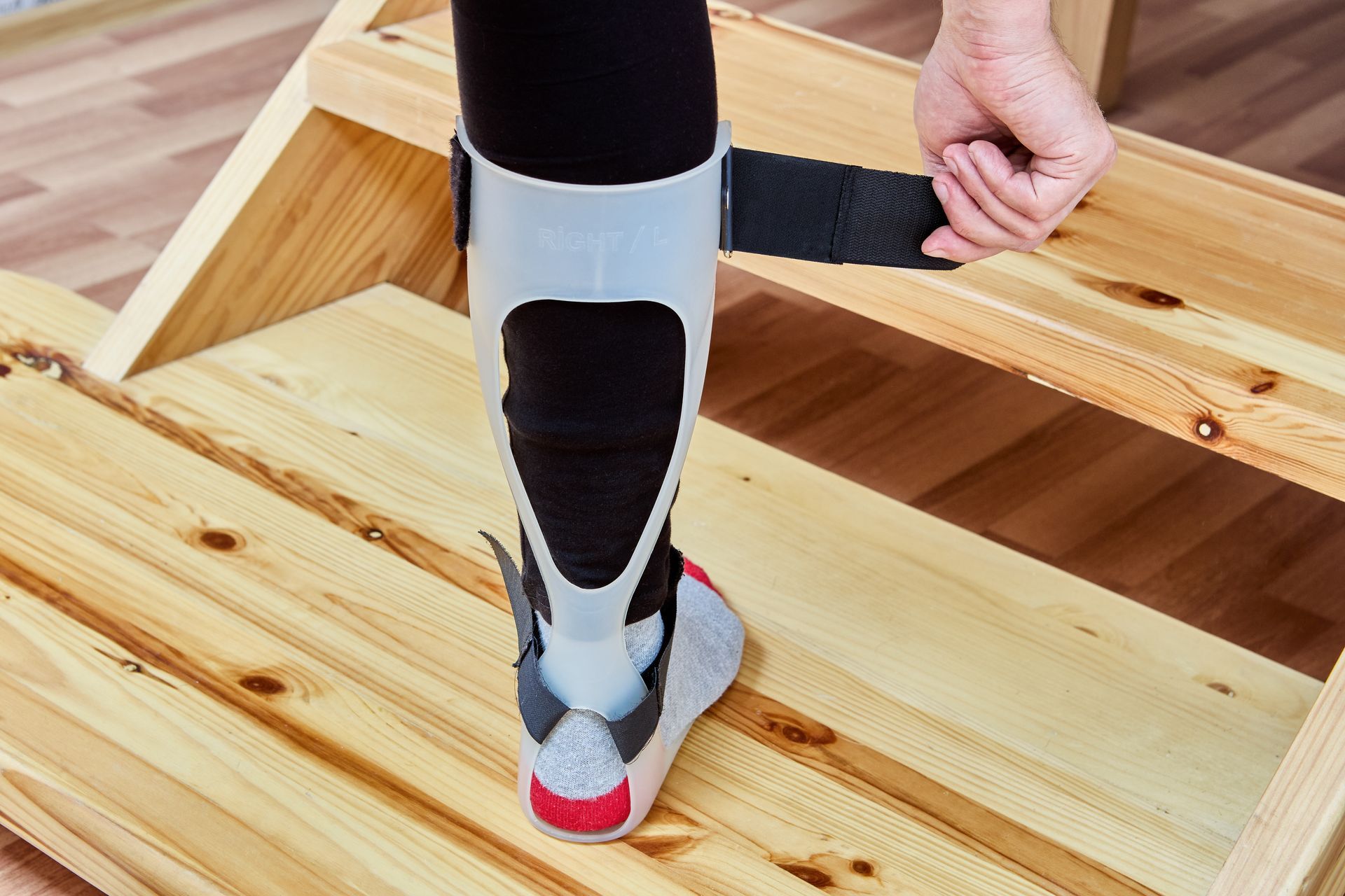 Person adjusting a leg brace on a wooden step.
