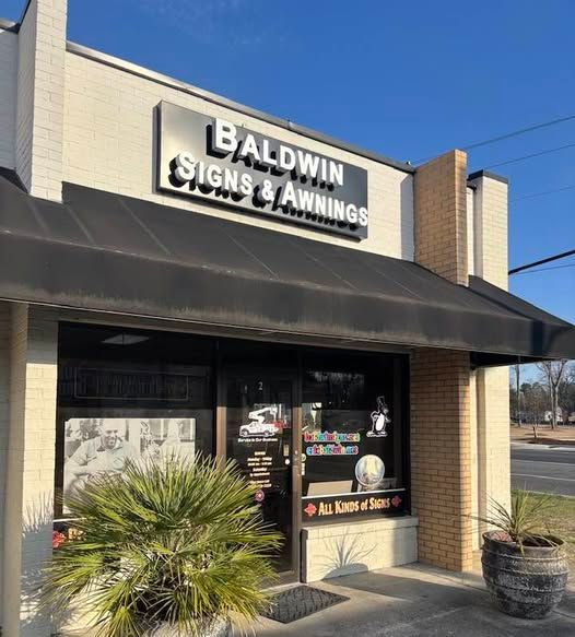 A Baldwin signs and awnings store with a black awning A aldwin signs and awnings store with a black awning