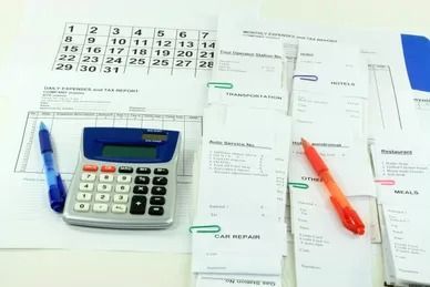 Calendar, calculator, receipts, and pens on a white surface, suggesting financial planning or accounting.