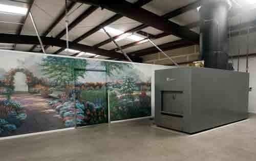 Indoor industrial space with a large gray metal enclosure and a painted mural wall under exposed beams