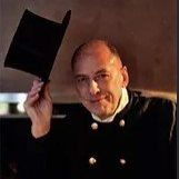 Un homme en costume noir tient un chapeau haut de forme dans sa main.