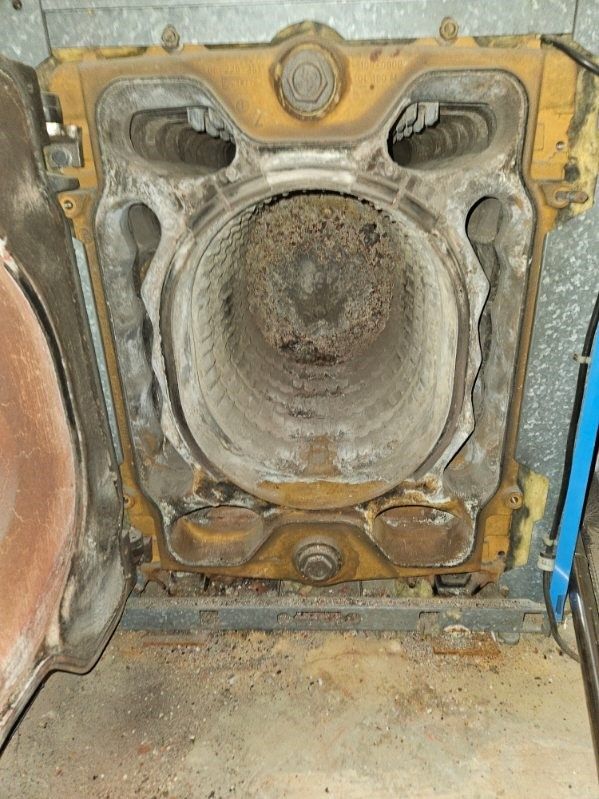 Un gros plan d'un poêle sale avec la porte ouverte.